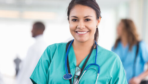 Friendly beautiful nurse smiling during shift at hospital